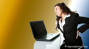 a person Montreal bending over a computer holding her back due to pain